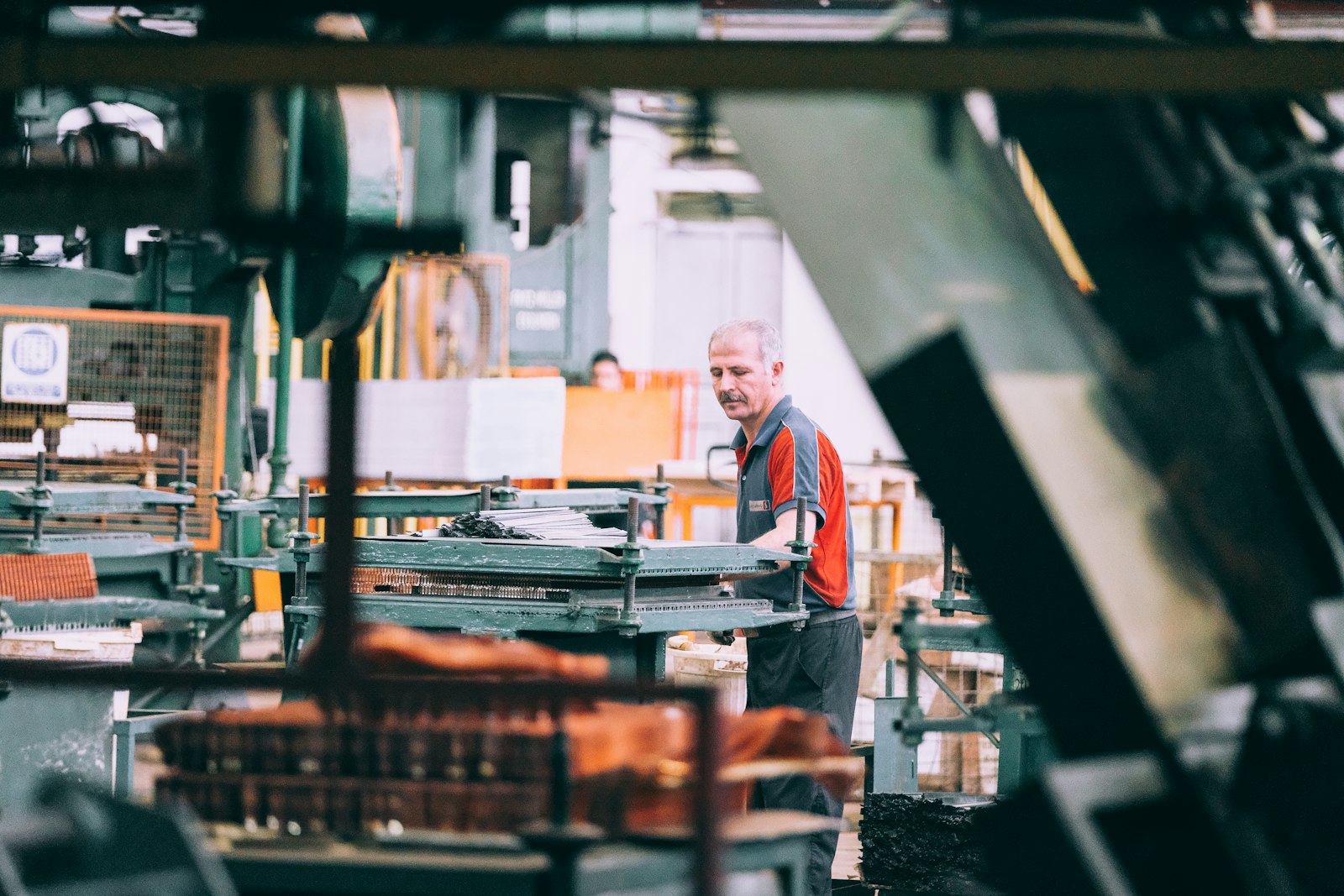 A worker operating machinery on a busy factory floor